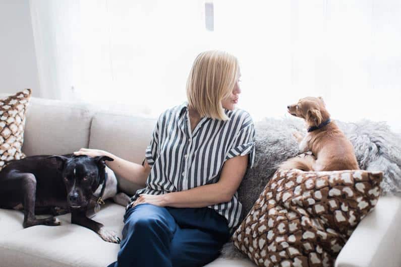 Social media design and style maven Anne Sage and her dogs on a sofa protected by Crypton Home Fabric flax linen