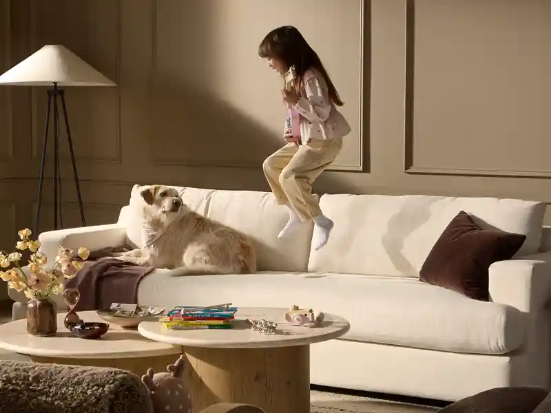 girl jumping on white couch with dog