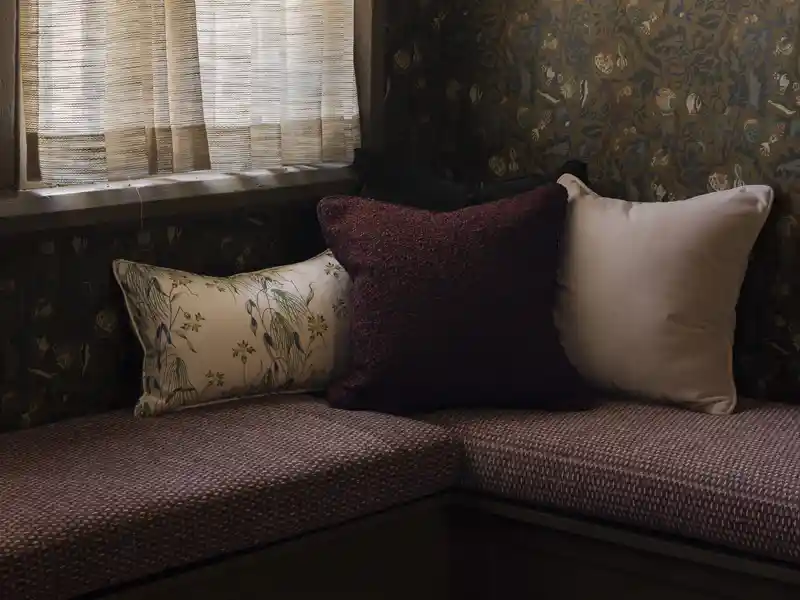 A cozy nook with banquette upholstered in burgundy color performance fabric in the newly designed Garden & Gun magazine headquarters