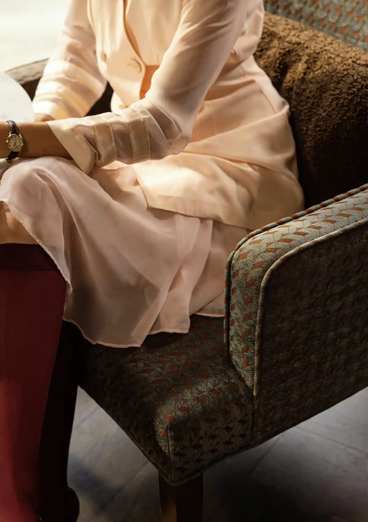 woman sitting in upholstered chair in hotel lobby